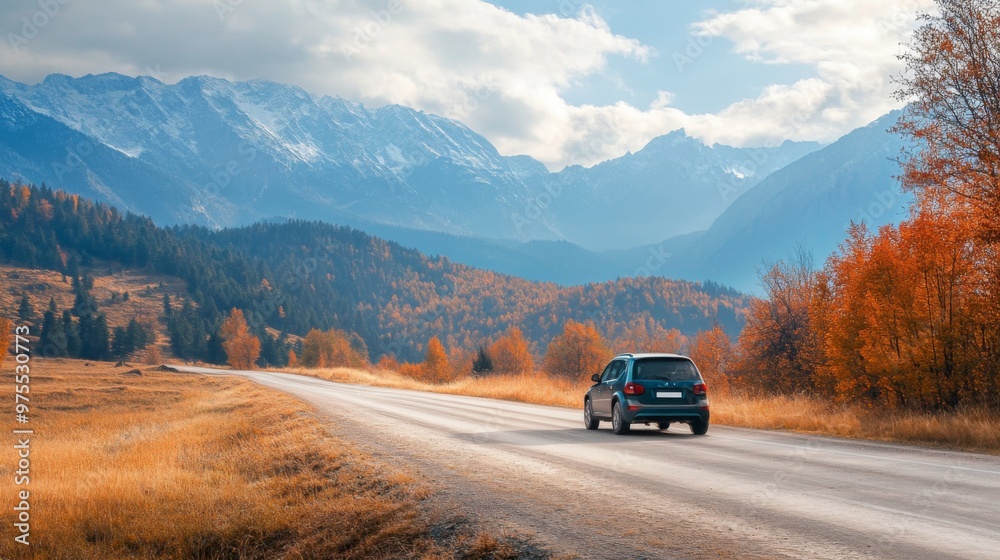 A car drives along a winding road through an autumnal landscape, with snow-capped mountains in the distance. A car drives along a winding road through an autumnal landscape, with snow-capped mountains in the distance.