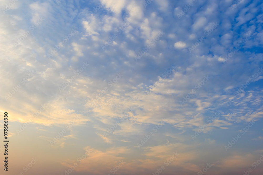 Fototapeta premium The morning sky with soft scattered clouds. The sky has a gradient from warm pale yellow below to cool light blue above. Cloud formations are soft and thin.