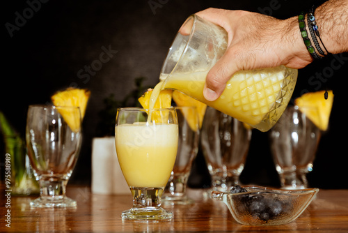 Tableau sur toile Male hands serving a refreshing piñacolada cocktail on black background
