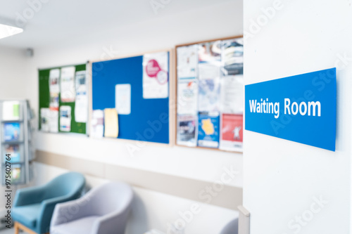 Shallow focus of a typical NHS hospital waiting room sign seen in a British hospital. Seating and information material can be seen in the room.