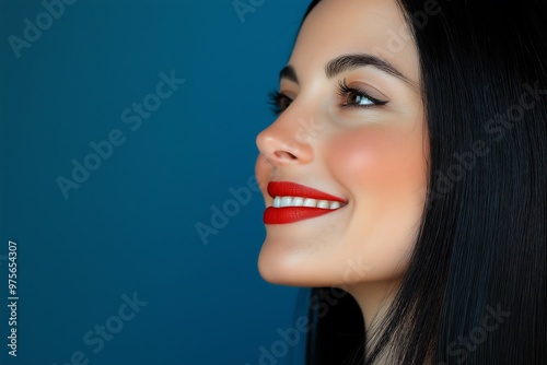 Close-up of actress Penelope Anatolis smiling. She has long, straight black hair and red lipstick on her lips photo