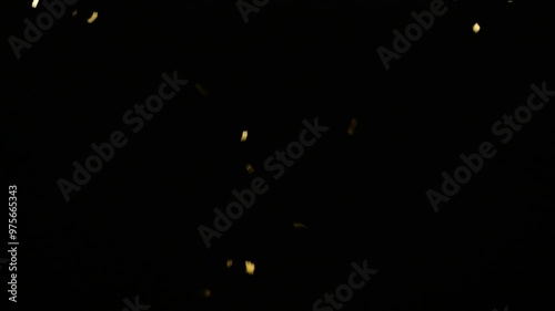 real gold confetti rain isolated on black background,  texture decoration overlay template for festive holiday celebrations