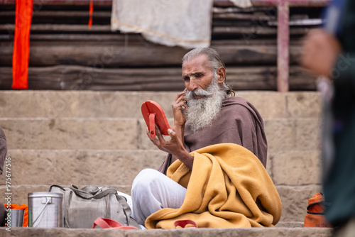 Portrait of an old sadhu baba sitting near the river bank during winter morning while getting ready to perform the hindu rituals during the kumbh fair. photo