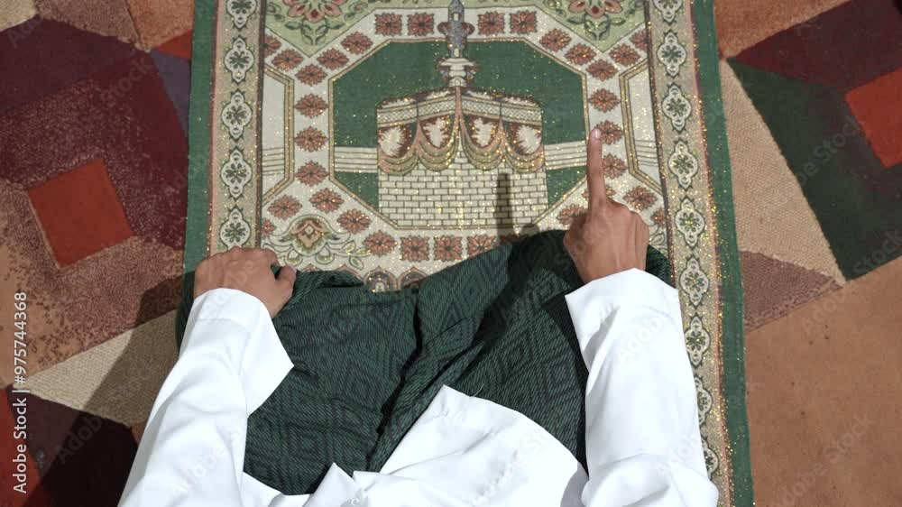 Young asian man with Muslim cap performing namaz or salat prayer sitting on knees at home