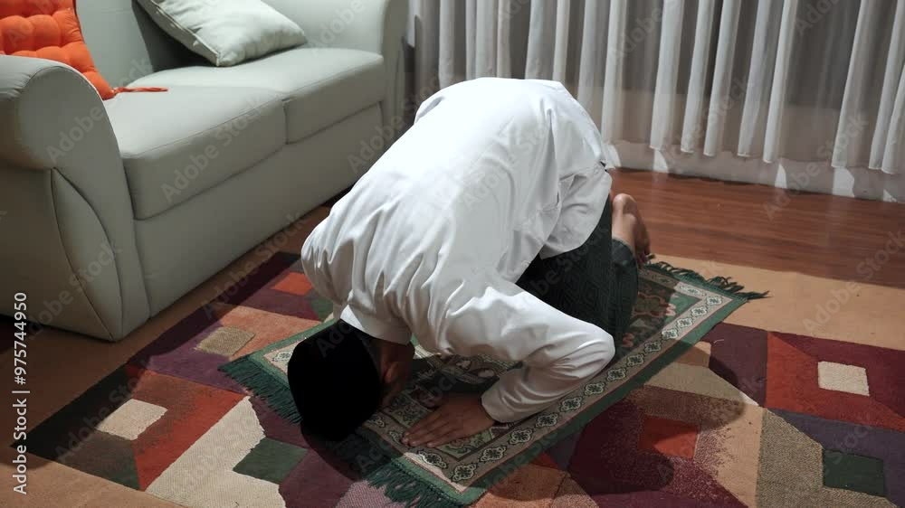 Young asian man with Muslim cap performing namaz or salat prayer sitting on knees at home