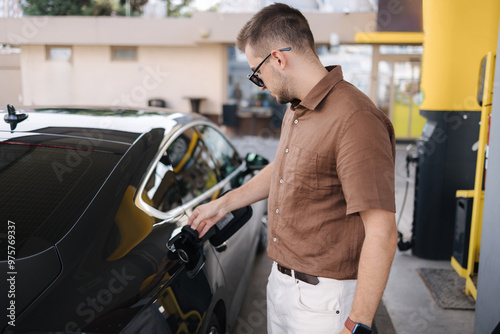 Man open tank on the car for refueling. Process of starting. Gas station. Luxury car photo