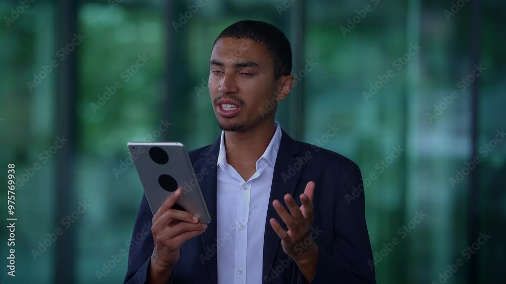 A young professional is deeply engaged with a tablet amidst a modern workspace environment A young professional is deeply engaged with a tablet amidst a modern workspace environment