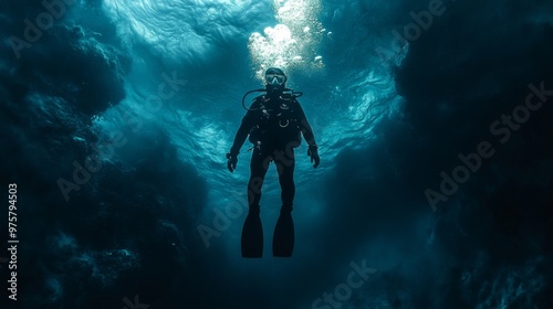 A scuba diver in a dark blue ocean with bubbles rising above.