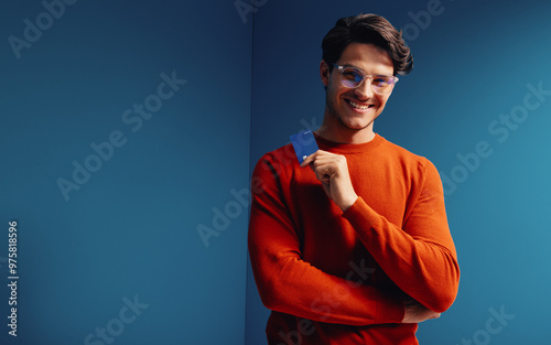 Young man with bank card in vibrant colorblocking environment depicting financial confidence photo