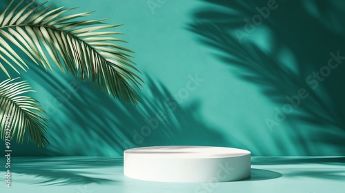 A single round pedestal platform in front of a green colored wall with palm leaves and shadows.