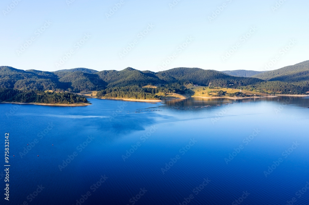 Lake and mountains surrounded by forests in Bulgaria. Fish farms of trout and other fish on the lake. Aerial shot with a drone Lake and mountains surrounded by forests in Bulgaria. Fish farms of trout and other fish on the lake. Aerial shot with a drone