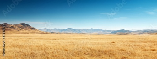  A scene of a field in the foreground, accompanied by a mountain backdrop, and a blue sky dotted with clouds