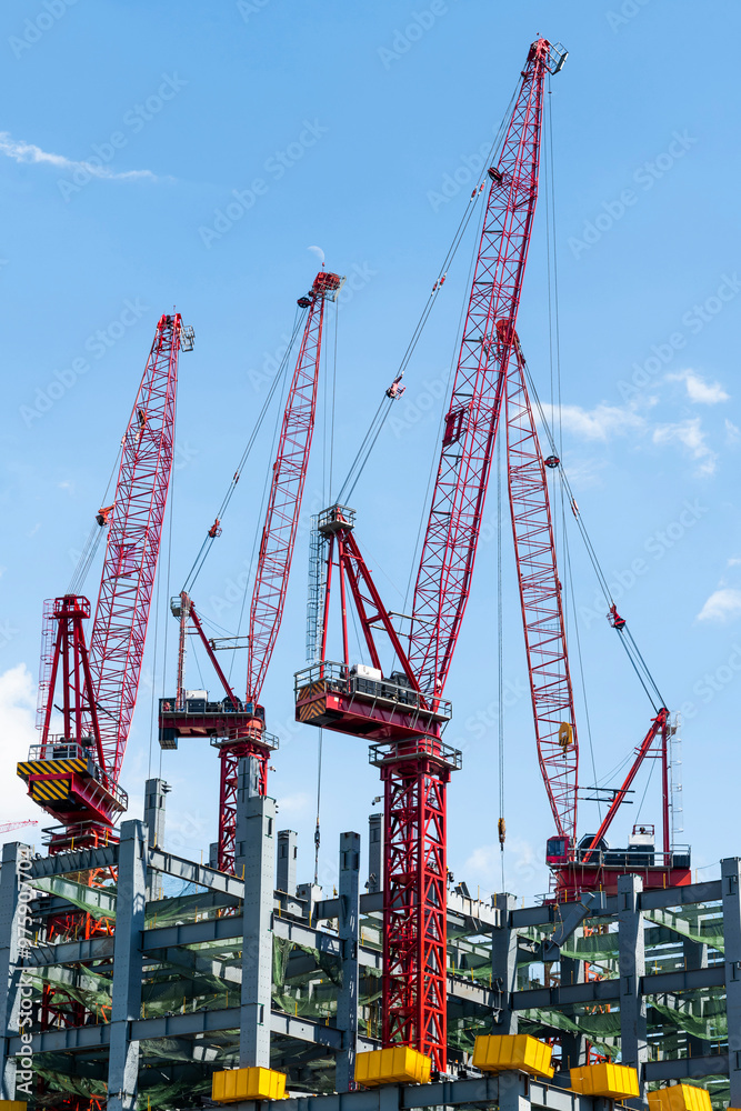 Low-angle view of cranes and steel structures of building construction with a blue sky background in Taiwan. Low-angle view of cranes and steel structures of building construction with a blue sky background in Taiwan.