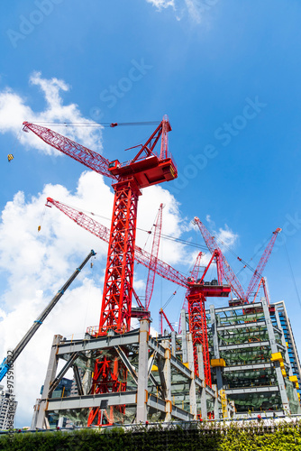 Low-angle view of cranes and steel structures of building construction with a blue sky background in Taiwan.