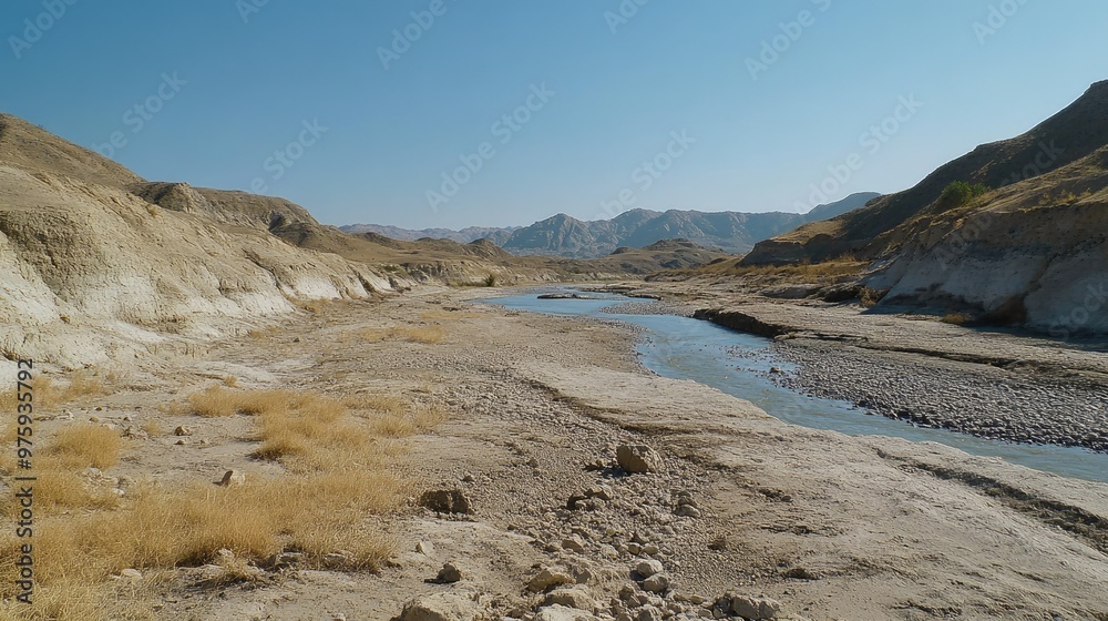 A dry riverbed winding through a valley, with no signs of water and only dry rocks and sand. A dry riverbed winding through a valley, with no signs of water and only dry rocks and sand.