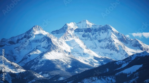 Snow-covered mountain peaks under a clear blue sky, with sunlight reflecting off the snow.