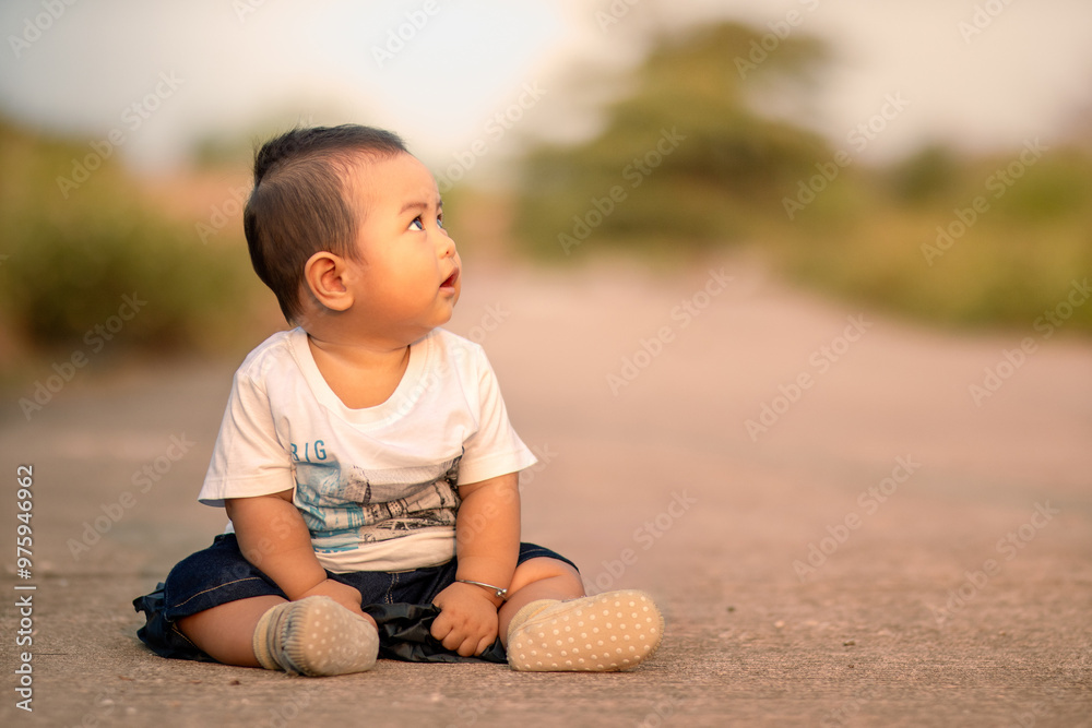 cute asian baby sitting on the road. baby boy facing sideways wearing white clothes. photo atmosphere in the afternoon. cute asian baby sitting on the road. baby boy facing sideways wearing white clothes. photo atmosphere in the afternoon.