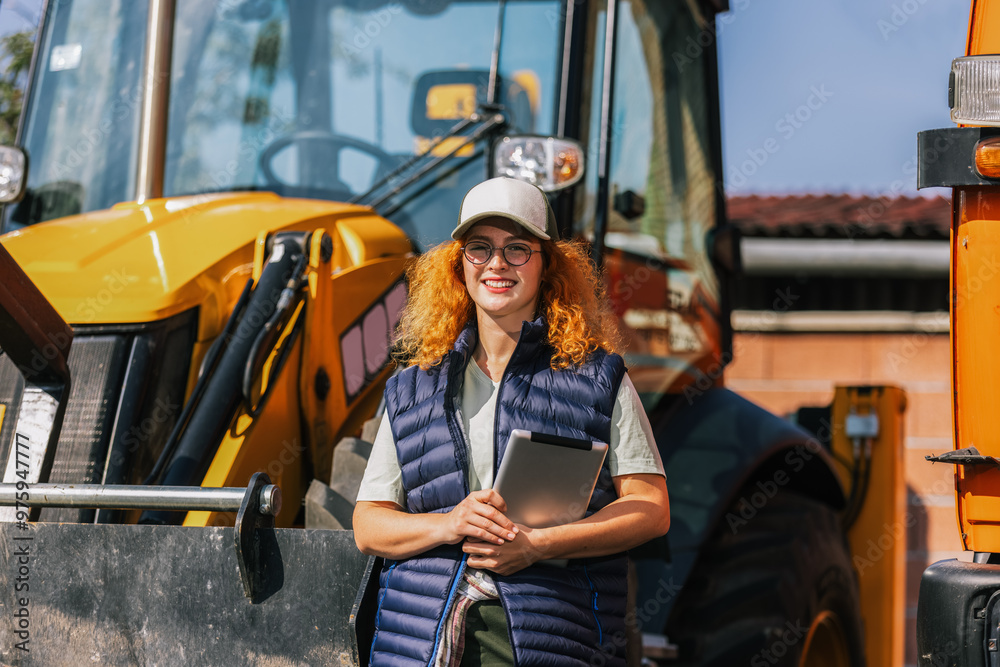 Ginger woman checking the excavator on her tablet.