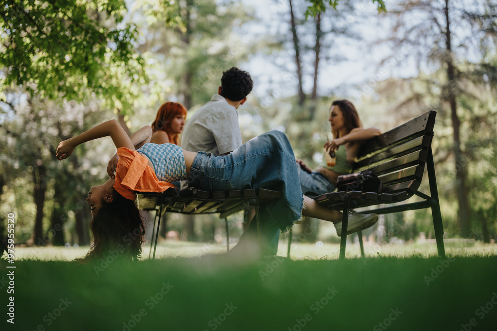 Group of young adults relaxing and chatting on a park bench on a sunny day, enjoying nature and friendship. Group of young adults relaxing and chatting on a park bench on a sunny day, enjoying nature and friendship.