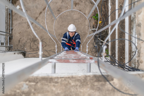 Engineer in Full Safety Gear Climbing a Ladder to Inspect Communication Signals and Industrial Machinery at a High-Risk Transportation Facility