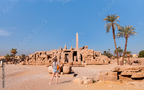 A beautiful young girl in shorts is standing examining historical artifacts - Ancient Temple of Karnak in Luxor - Ruined Thebes Egypt photo