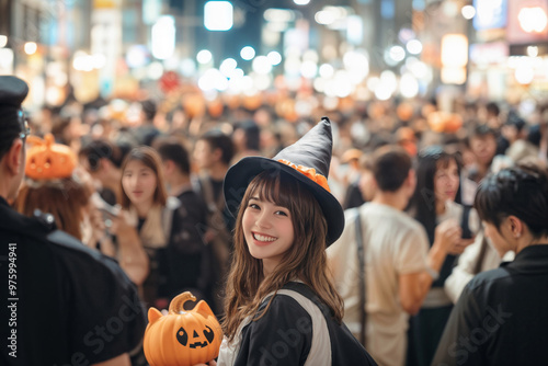 ハロウィーンの夜、渋谷の繁華街・交差点の大通りの人混みの中で魔女の仮装をして微笑む若い日本人女性(美人モデル) photo