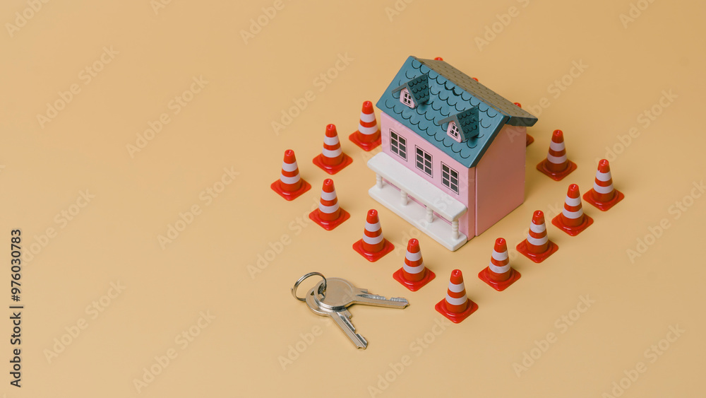 A house is surrounded by orange and white cones. A key is laying on the ground in front of the house, Concept of caution and warning, as if the debt is being protected from potential harm