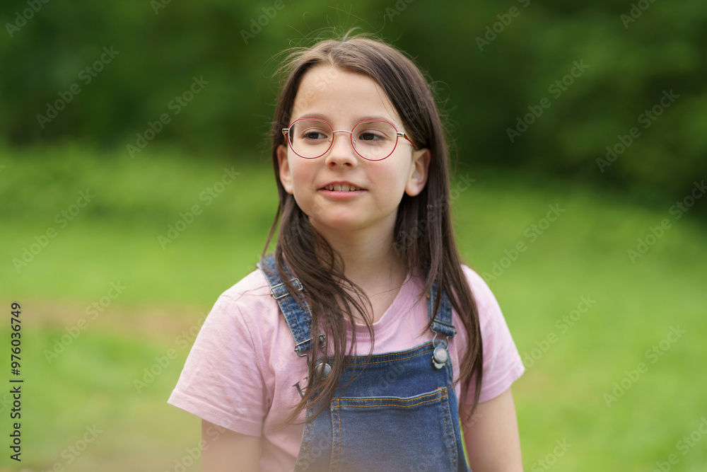 Little beautiful girl in glasses on bright green natural background. Happy childhood concept outdoors Little beautiful girl in glasses on bright green natural background. Happy childhood concept outdoors