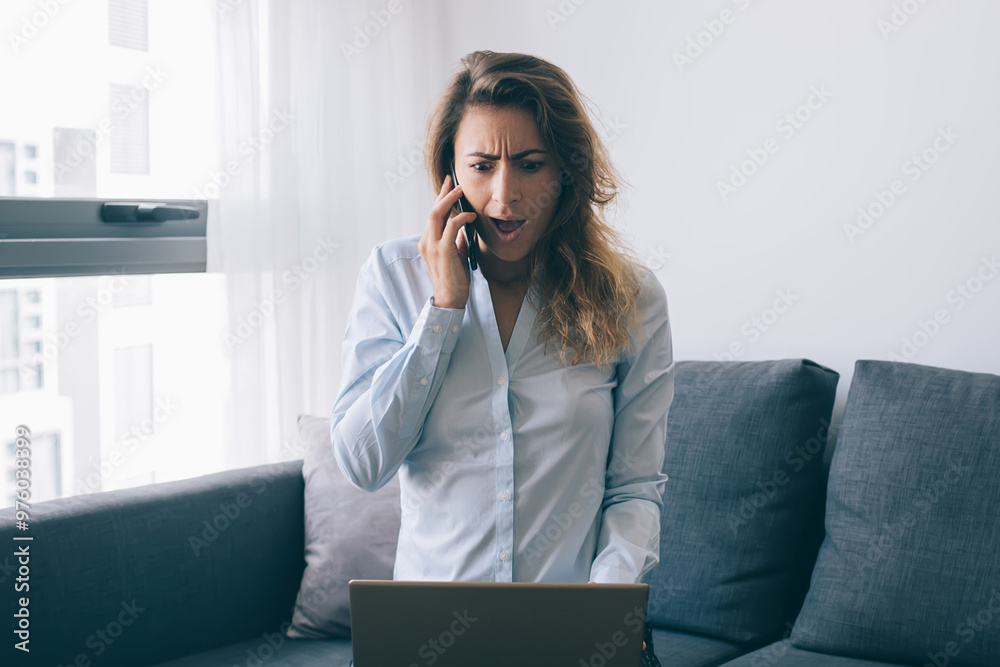 Amazed woman calling on phone and watching laptop Amazed woman calling on phone and watching laptop