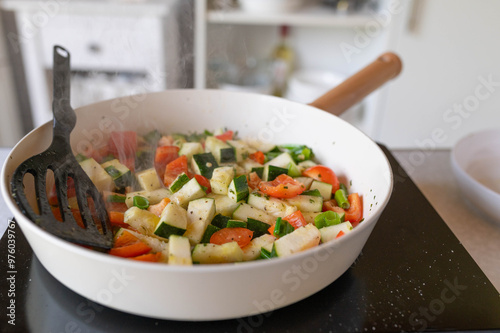 Canvas Print Fresh cubed vegetable frying in a frying pan with steam