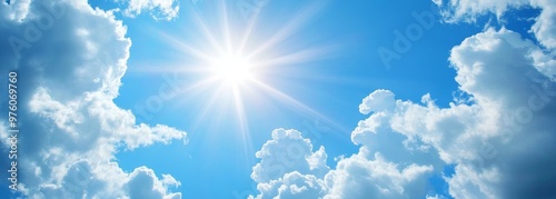 Shining sun through fluffy clouds on blue clean sky background