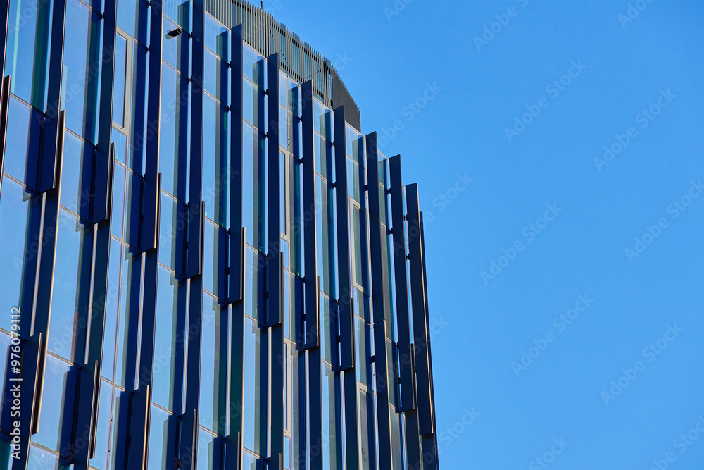 Close-up of modern glass building facade with geometric patterns reflecting sky. Contemporary architectural design. Close-up of modern glass building facade with geometric patterns reflecting sky. Contemporary architectural design.