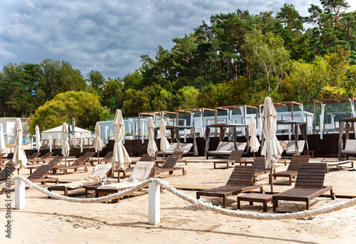 Fototapeta Naklejka Na Ścianę i Meble -  Wooden sun loungers with umbrellas and gazebos with white curtains on the shore of the Baltic Sea in Jurmala, Latvia