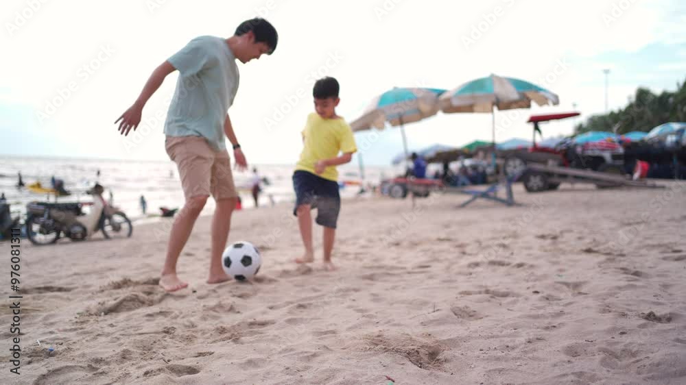 Asian man and child are enjoy playing football at the beach. Asian man and child are enjoy playing football at the beach.