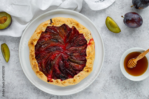 Homemade Galette with plum and honey on a light background. Summer pastry. Shortcrust dough. Zwetschgenkuchen. German cousine photo