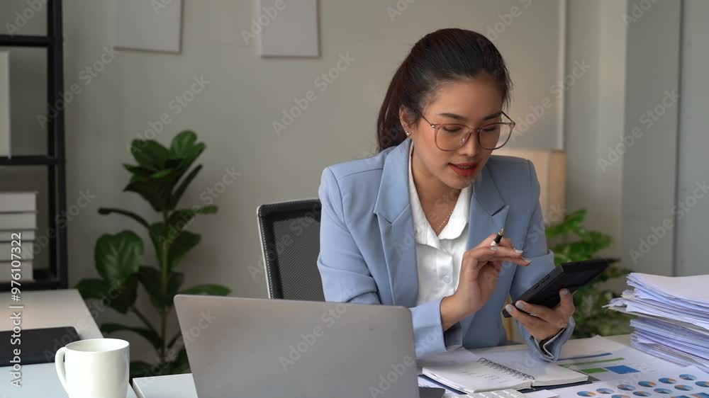 young Asian woman using the laptop and discussing on the phone in the office. Startup business concept. young Asian woman using the laptop and discussing on the phone in the office. Startup business concept.