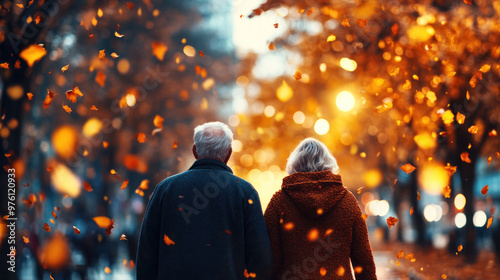 An elderly couple walking hand-in-hand through a peaceful park, the autumn leaves gently falling around them. photo