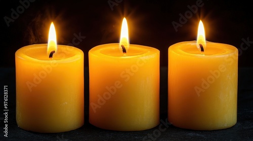 A group of three yellow candles sitting on top of a table.