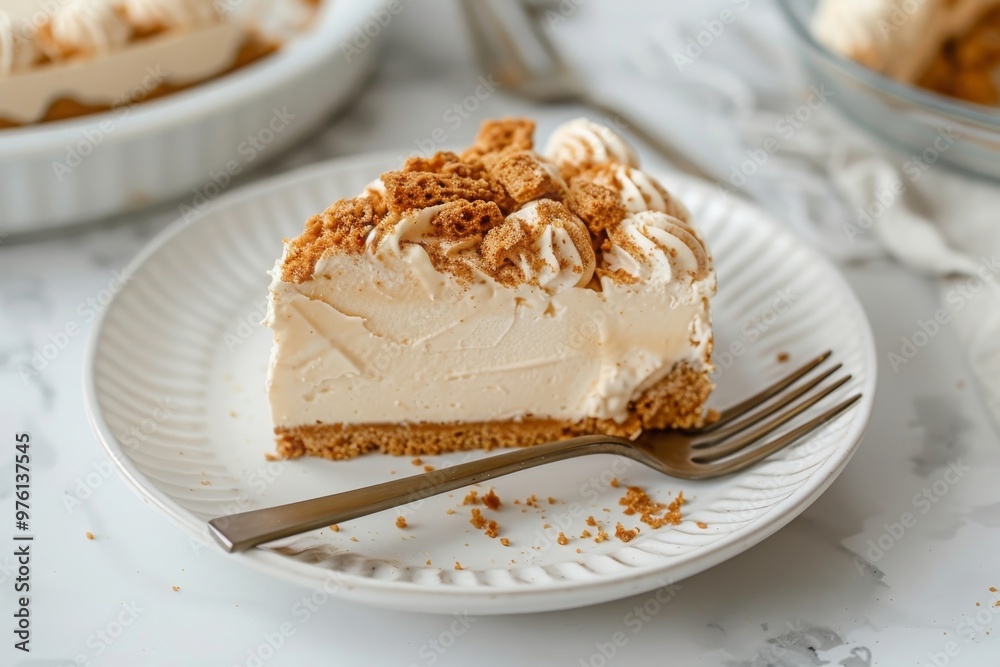 A slice of no-bake lotus biscoff cheesecake on a white plate along with fork on a white background A slice of no-bake lotus biscoff cheesecake on a white plate along with fork on a white background
