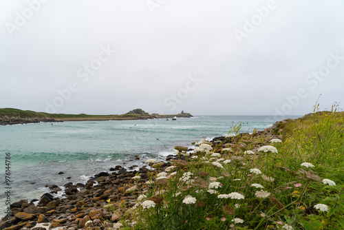 Journée printanière sous un ciel couvert, à marée haute sur la plage de Penfoul avec des eaux émeraude et des carottes sauvages blanches en premier plan, dans le Finistère nord. photo