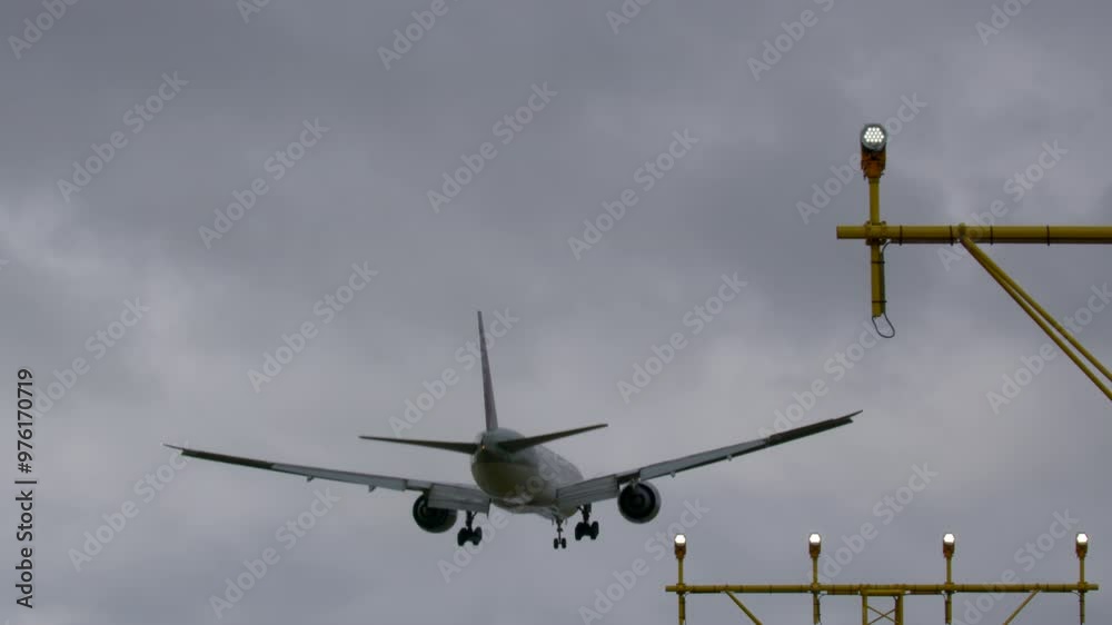 Airplane descending towards the runway with its landing gear deployed, captured from the rear view as it prepares to land Airplane descending towards the runway with its landing gear deployed, captured from the rear view as it prepares to land