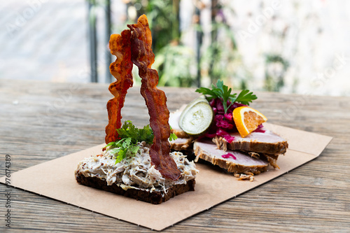 Photography Danish open sandwich with meat salad, pork slices, bacon on wooden table outdoor
