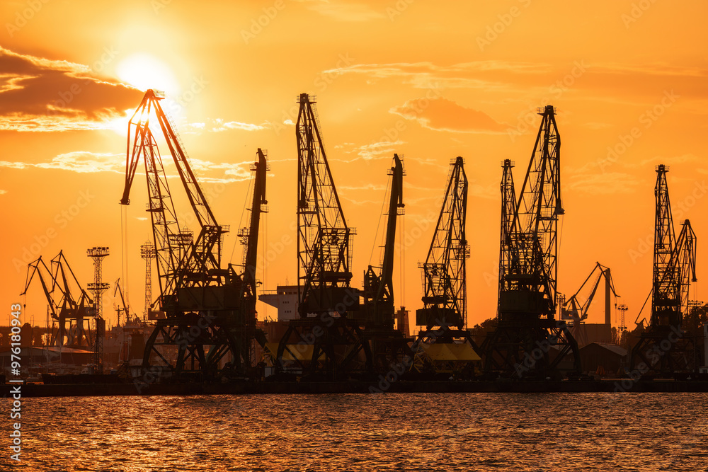 Sea port and industrial cranes silhouettes, Varna, Bulgaria. Sunset over Varna lake. Sea port and industrial cranes silhouettes, Sunset city landscape Sea port and industrial cranes silhouettes, Varna, Bulgaria. Sunset over Varna lake. Sea port and industrial cranes silhouettes, Sunset city landscape
