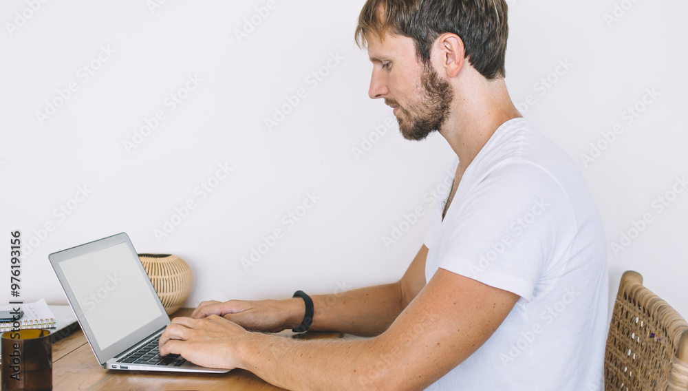 Side view of serious male software developer working online on modern netbook with blank screen for advertising text or your website information connecting to high 4g internet, distance job Side view of serious male software developer working online on modern netbook with blank screen for advertising text or your website information connecting to high 4g internet, distance job