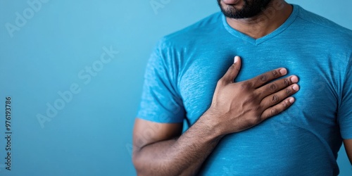 A man wearing a blue shirt places his hand on his chest, conveying a sense of emotion or gratitude in a simple, yet powerful composition.