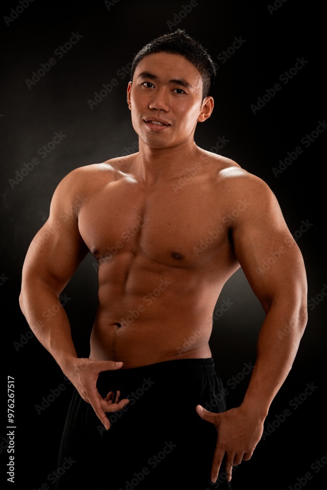 Fototapeta premium Musculat asian man bodybuilder posing against black background.