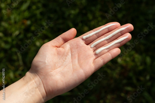 A person applying the correct amount of sunscreen for face and neck (three finger lengths).