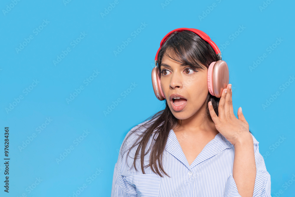Surprised Woman Enjoying Music With Colorful Headphones Against Vibrant Blue Background Surprised Woman Enjoying Music With Colorful Headphones Against Vibrant Blue Background