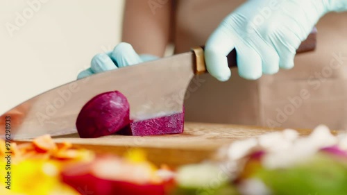 Close up of female hands in gloves cutting beet on kitchen board