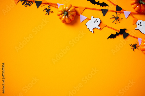 Halloween party decorations, pumpkins, garland, ghosts, spiders, bats on orange background. Happy Halloween holiday greeting card template. Flat lay, top view, copy space. photo